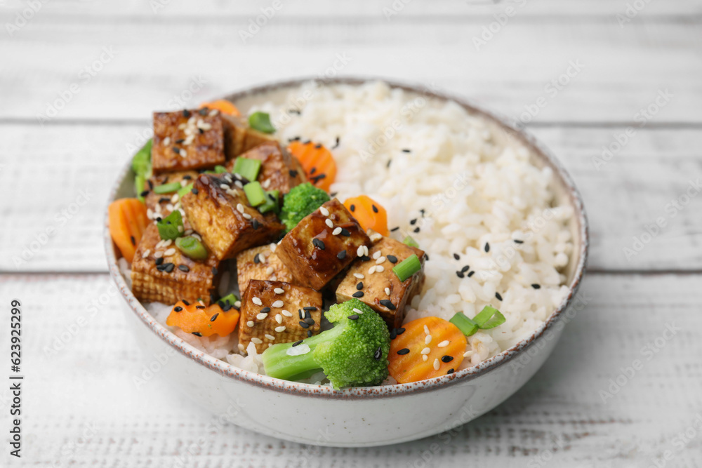 Bowl of rice with fried tofu, broccoli and carrots on white wooden table, closeup Bowl of rice with fried tofu, broccoli and carrots on white wooden table, closeup