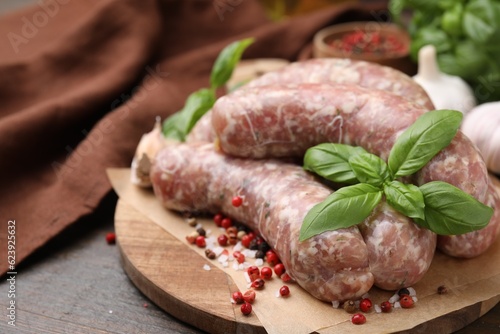 Raw homemade sausages and different spices on wooden table, closeup. Space for text