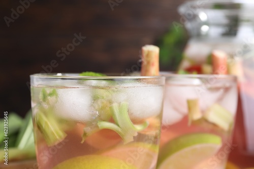 Glasses of tasty rhubarb cocktail with citrus fruits on blurred background, closeup
