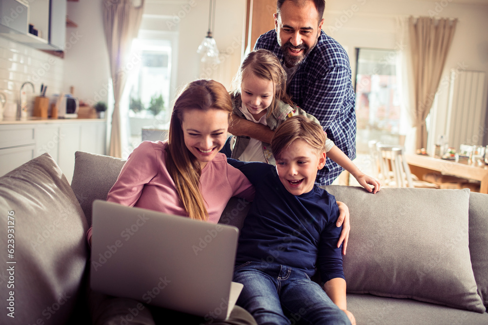 Young family spending time together at home and using a laptop on the couch