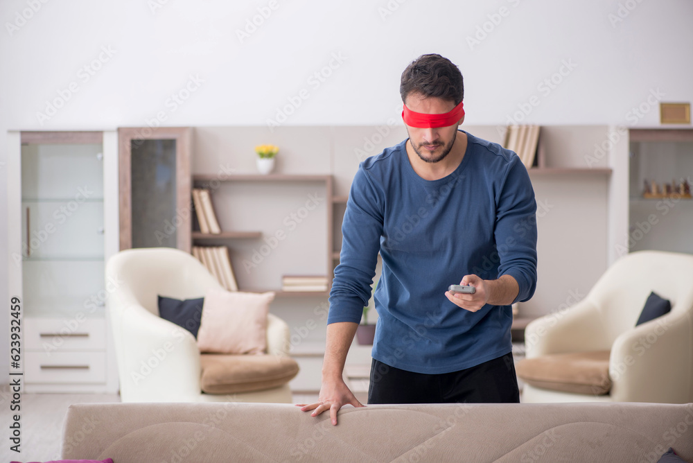 Blindfolded young man watching tv at home