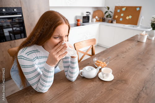 Allergic young woman sneezi...