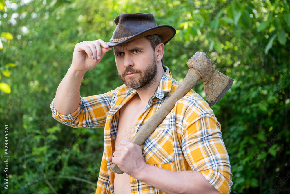 Obraz premium photo of male cowboy with axe. cowboy with axe. cowboy with axe wearing checkered shirt.