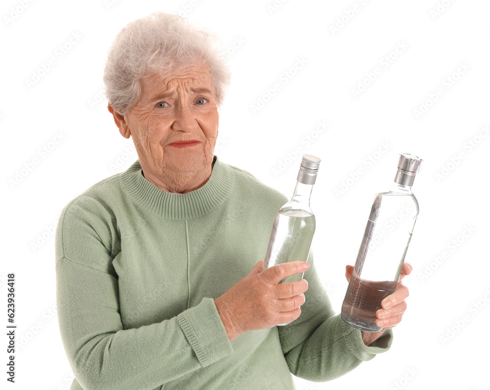 Displeased senior woman with bottles of vodka on white background Displeased senior woman with bottles of vodka on white background