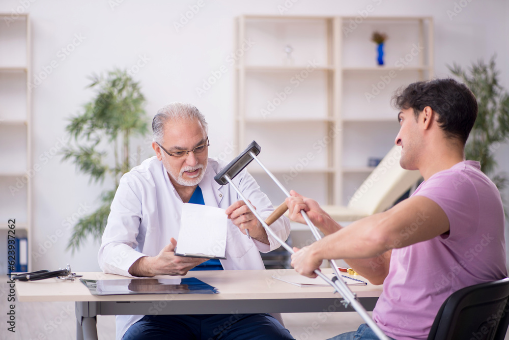Young leg injured patient visiting old male doctor Young leg injured patient visiting old male doctor