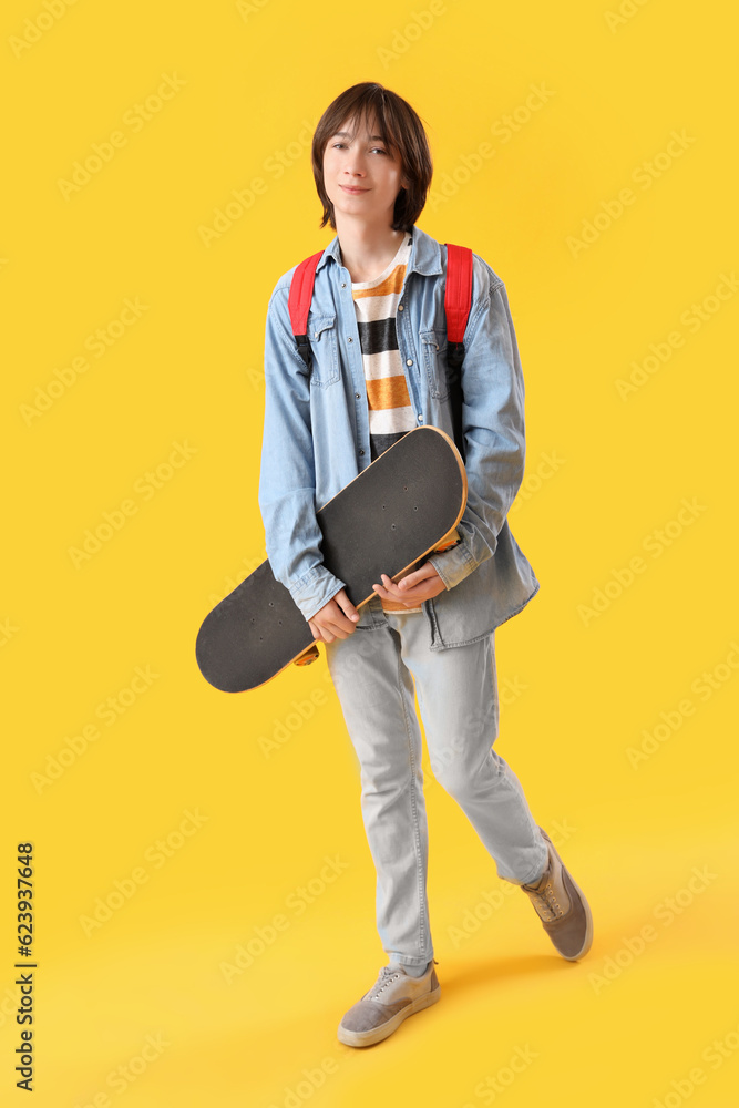 Male student with skateboard on yellow background Male student with skateboard on yellow background