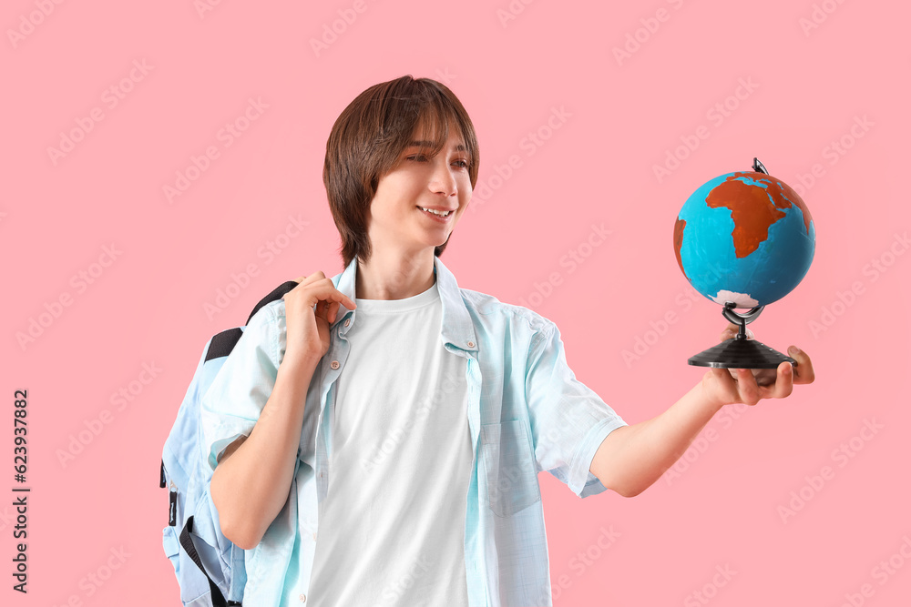 Fototapeta premium global education and international study, young student holding a globe with a backpack on a pink background