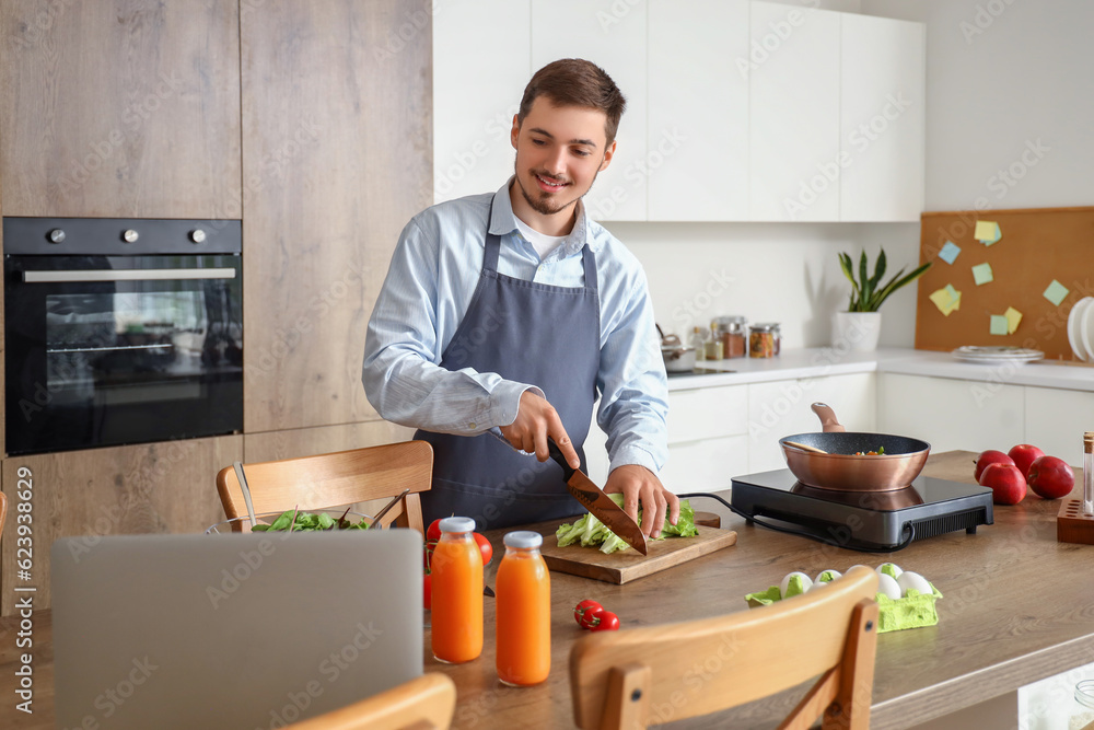 Young man cutting lettuce a table in kitchen Young man cutting lettuce a table in kitchen