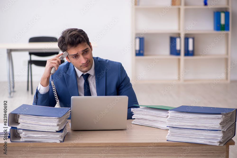 Young male employee and too much work in the office Young male employee and too much work in the office