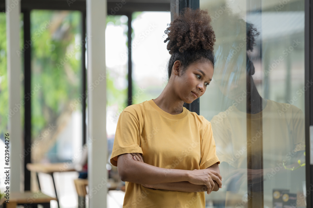 Young pretty African American standing and arms crossed near a window. Young pretty African American standing and arms crossed near a window.