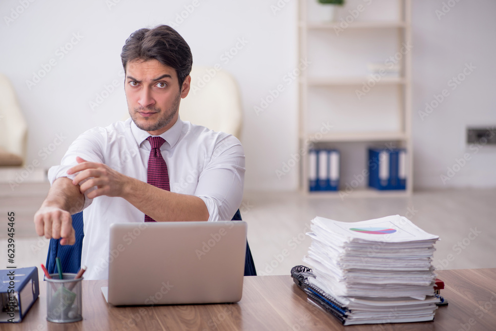 Young male employee unhappy with excessive work in the office Young male employee unhappy with excessive work in the office