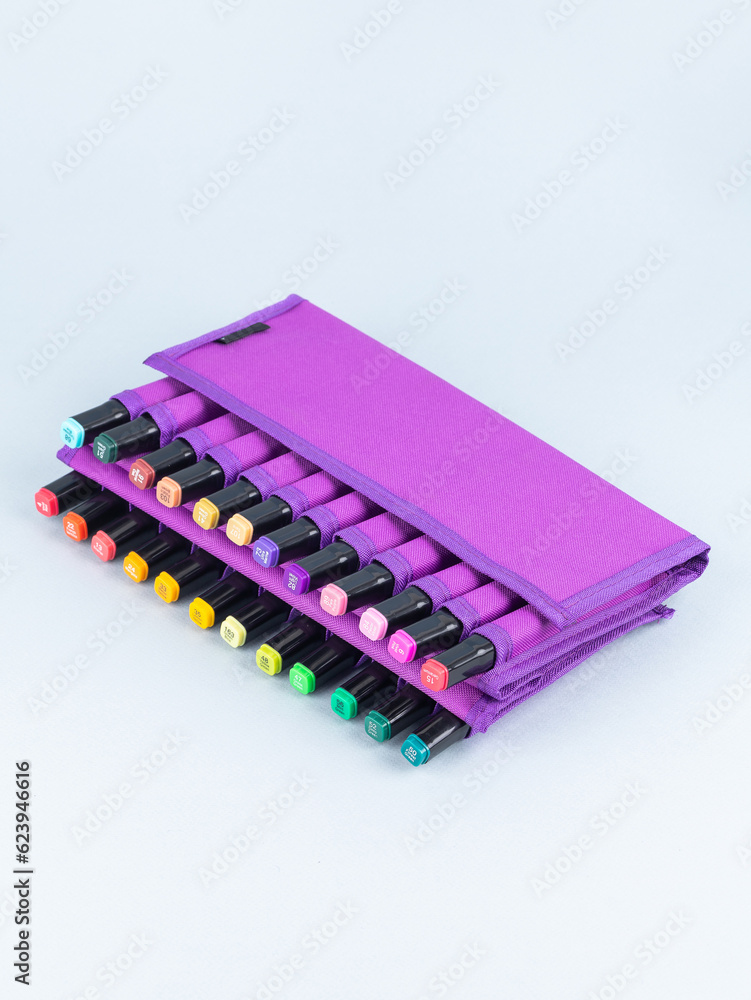 A set of professional markers in a purple case on a light background. Markers for sketching are many colors. A set of professional markers in a purple case on a light background. Markers for sketching are many colors.