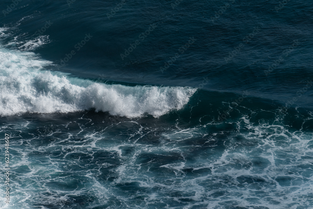 Fototapeta premium The waves of the ocean water meet with underwater pointed rocks