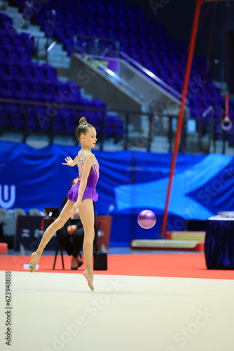 girl gymnast performs an exercise with a ball