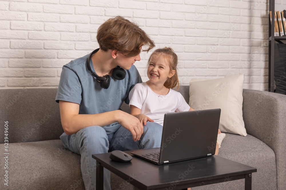 Brother And Sister Sitting On Sofa At Home Having Fun Playing On Laptop Together Brother And Sister Sitting On Sofa At Home Having Fun Playing On Laptop Together