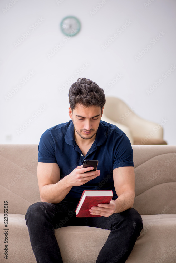 Young male student reading book at home Young male student reading book at home