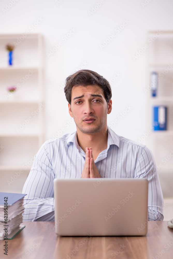 Young male employee and too much work in the office Young male employee and too much work in the office
