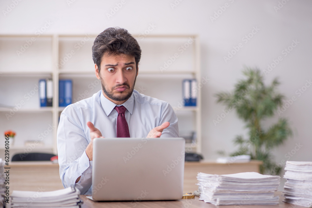 Young male employee and too much work in the office Young male employee and too much work in the office