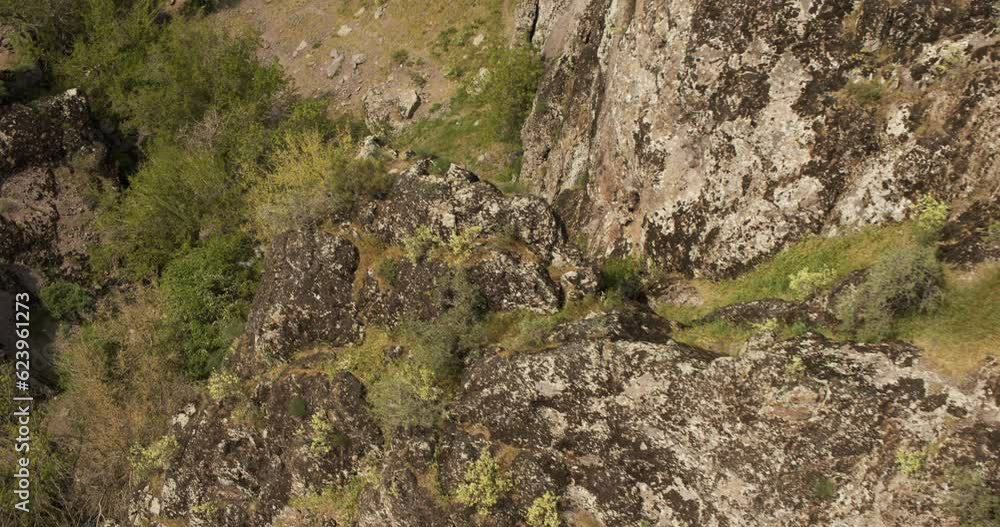A drone flies around a young athletic climber standing on a steep cliff A drone flies around a young athletic climber standing on a steep cliff