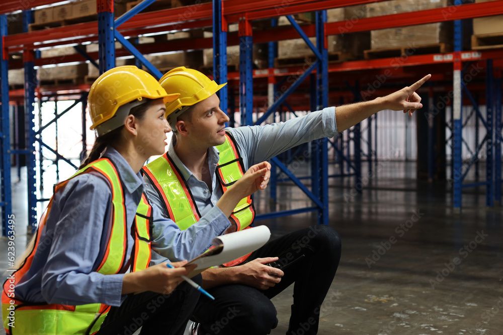 Group of warehouse workers with hardhats and reflective jackets using tablet, walkie talkie radio and cardboard while controlling stock and inventory in retail warehouse logistics, distribution center Group of warehouse workers with hardhats and reflective jackets using tablet, walkie talkie radio and cardboard while controlling stock and inventory in retail warehouse logistics, distribution center