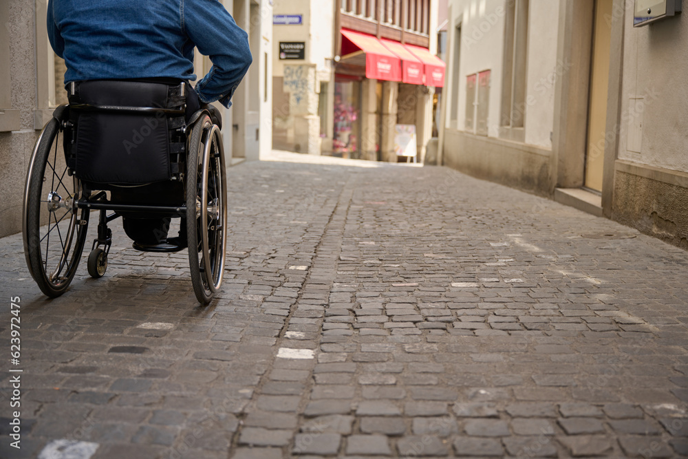 person in wheelchair on cobbled street in old own