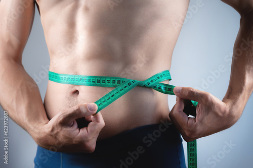 Caucasian man, fitness and body, measuring tape and abs with health, weight loss and active lifestyle. Shirtless bodybuilder healthy and strong