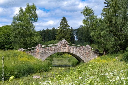 Ancient stone bridge on the Slavyanka river on a cloudy July day. Pavlovsk, suburbs of St. Petersburg. Russia photo