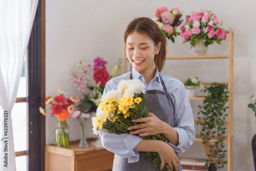 Florist concept, Woman florist smiling and holding white and yellow chrysanthemum in flower shop