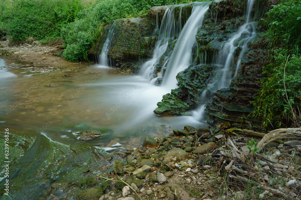 Fototapeta premium waterfall in a mountain river of crystalline waters with green vegetation, silk effect