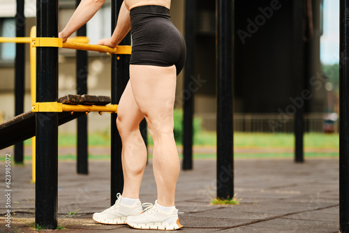 Muscular legs of bodybuilder on sports ground