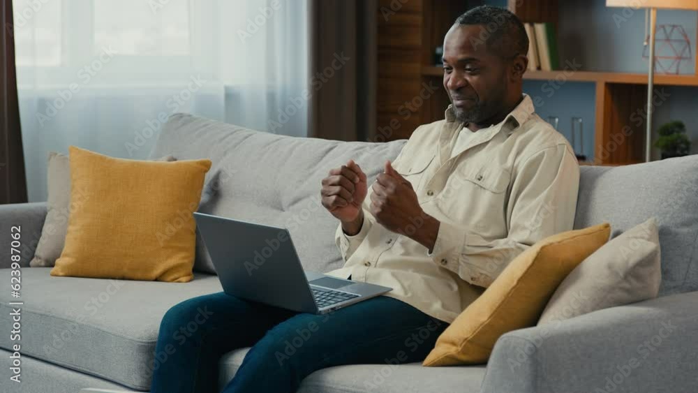Happy african american man businessman freelancer online teacher talking on video call using laptop at home couch distant business meeting talk with friends chatting in virtual conference speak remote Happy african american man businessman freelancer online teacher talking on video call using laptop at home couch distant business meeting talk with friends chatting in virtual conference speak remote