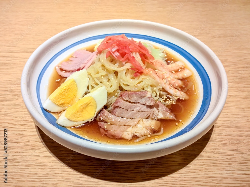 Cold ramen noodle with soup, roast pork, shrimp, ham, egg, mayonnaise, pickled ginger and sprinkled with sesame seeds.This combination of ingredients in the same bowl make the taste very delicious Cold ramen noodle with soup, roast pork, shrimp, ham, egg, mayonnaise, pickled ginger and sprinkled with sesame seeds.This combination of ingredients in the same bowl make the taste very delicious
