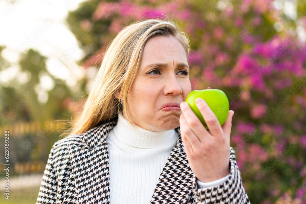 Young blonde woman with an apple at outdoors Young blonde woman with an apple at outdoors