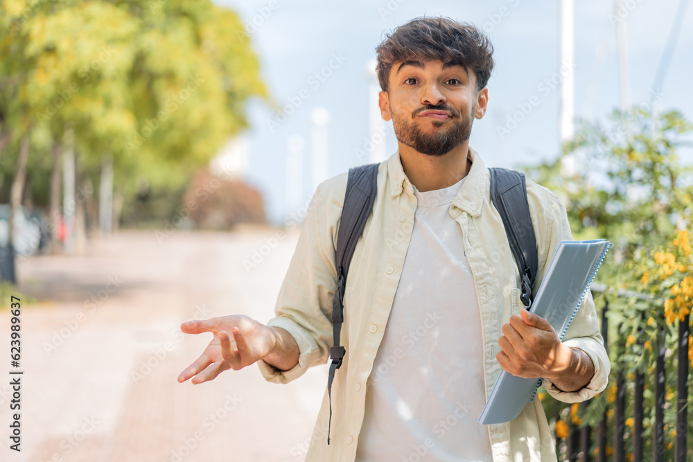 © luismolinero - Young student Arabian man at outdoors making doubts gesture while lifting the shoulders