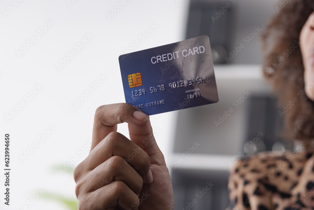 Fototapeta premium Young African American businesswoman holding credit cards with smartphone sitting at a desk in office. shopping online,