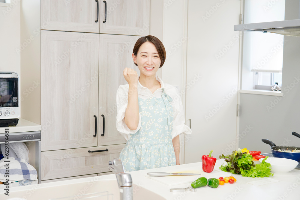 キッチンでガッツポーズするミドルエイジ女性