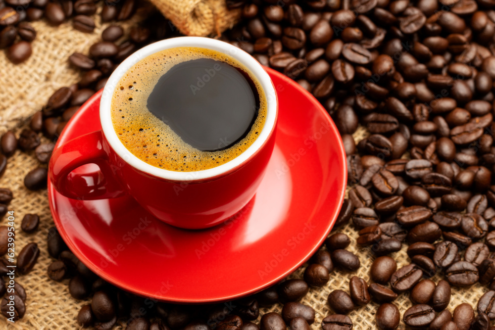 Black coffee or hot tea in a red coffee cup cappuccino espresso Breakfast with coffee beans on wooden table Isolated on black background. Top view.