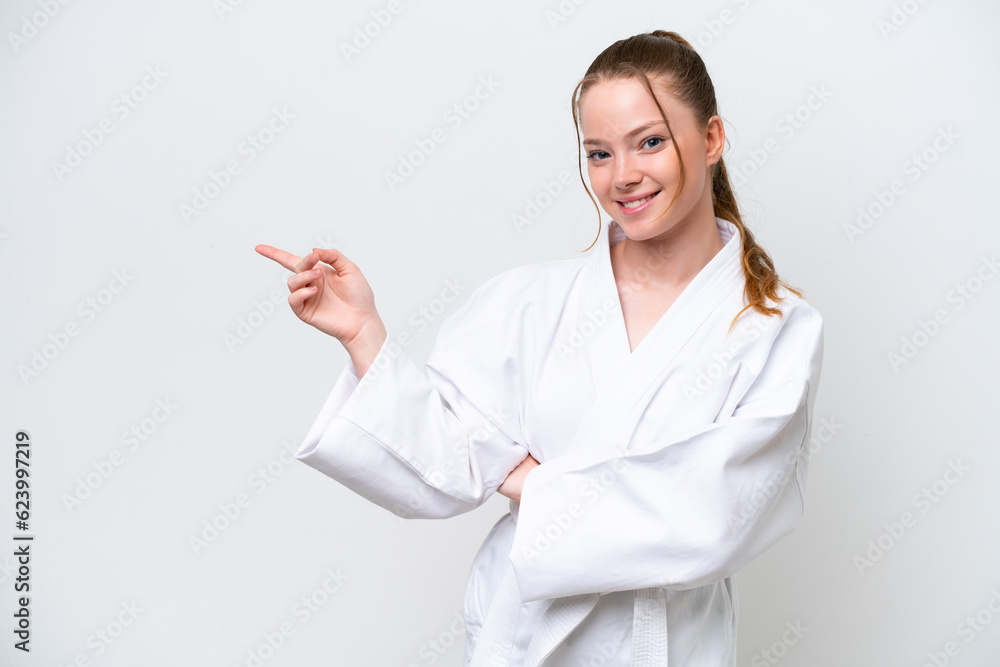 Young caucasian girl doing karate isolated on white background pointing finger to the side Young caucasian girl doing karate isolated on white background pointing finger to the side