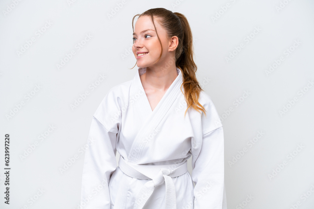 Young caucasian girl doing karate isolated on white background looking side Young caucasian girl doing karate isolated on white background looking side