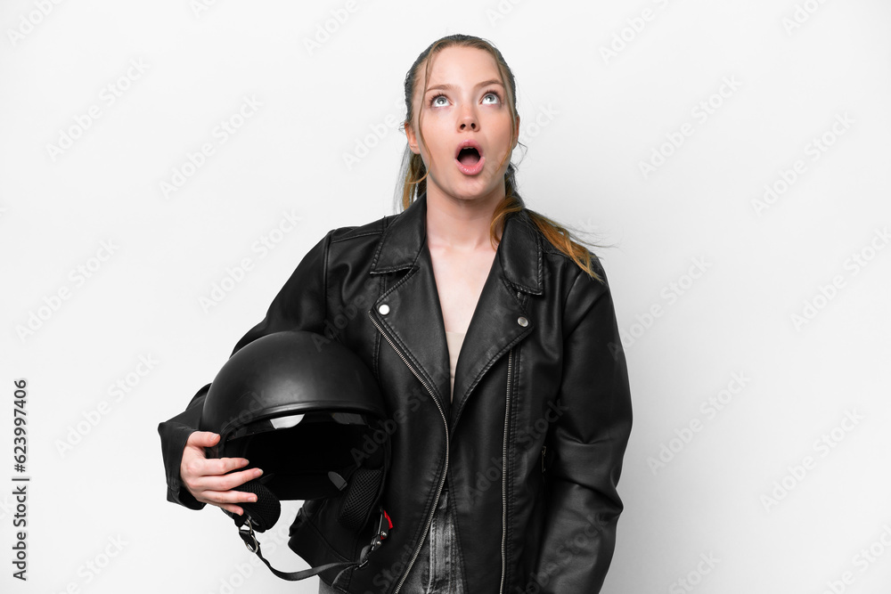 Fototapeta premium Young caucasian girl with a motorcycle helmet isolated on white background looking up and with surprised expression