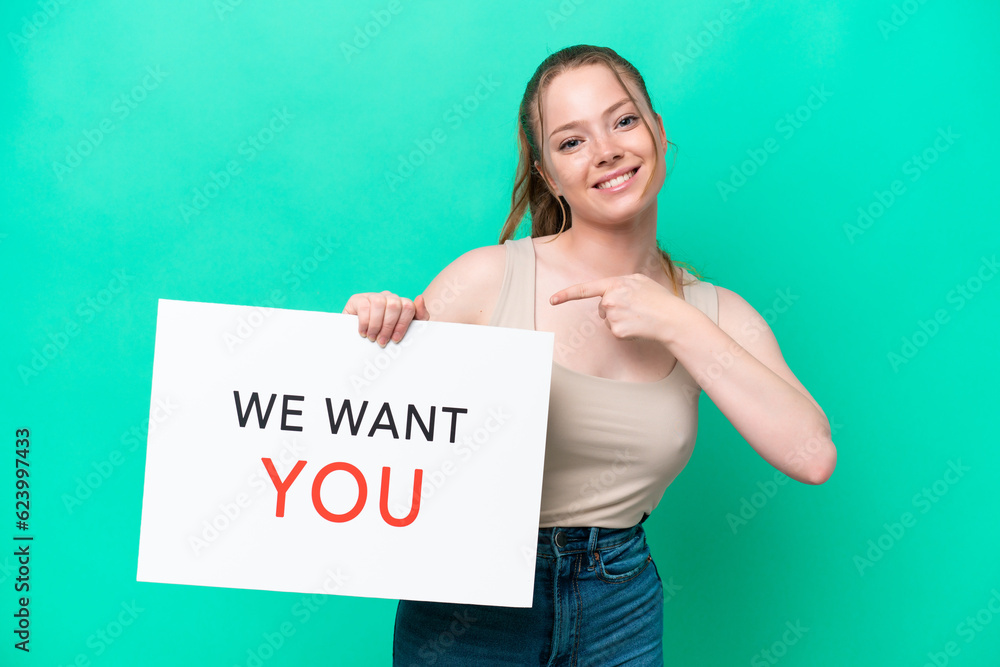 Young caucasian woman isolated on green background holding We Want You board and pointing it Young caucasian woman isolated on green background holding We Want You board and pointing it