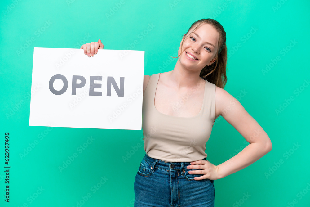 Young caucasian woman isolated on green background holding a placard with text OPEN with happy expression Young caucasian woman isolated on green background holding a placard with text OPEN with happy expression