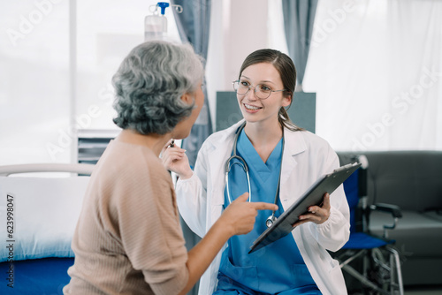 Female doctor in white medical coat discussing elderly patient in clinic, therapist. Consulting woman examining pain, health care, medicine concept.
