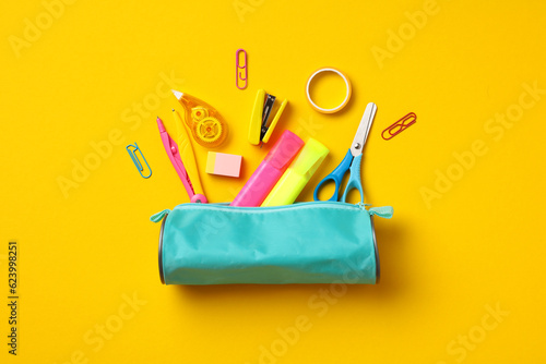Фотография Pencil case with school supplies on yellow background