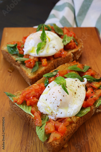 Delectable Pair of Toast with Poached Egg on Fresh Tomatoes and Basil Leaves