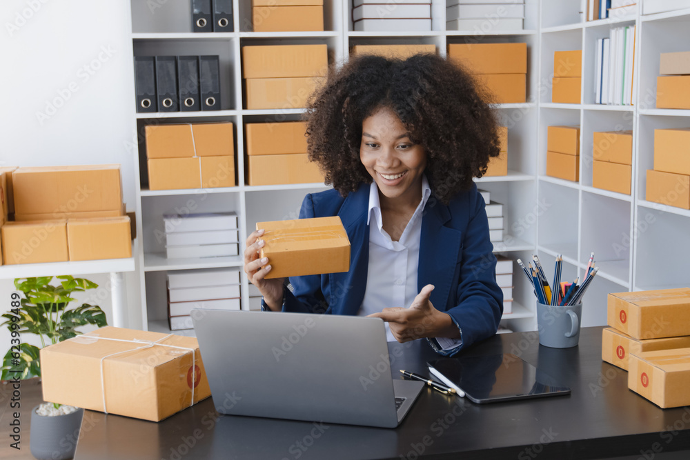 African American owner checking orders from customers sitting at desk in office, sell products online concept. African American owner checking orders from customers sitting at desk in office, sell products online concept.