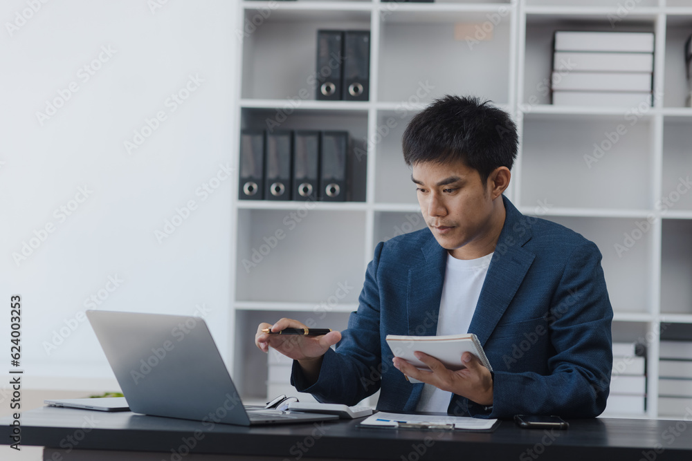 Asian businessman working online with laptop at desk in office, businessman online training concept. Asian businessman working online with laptop at desk in office, businessman online training concept.