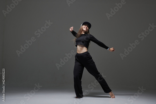 a girl in dark clothes dances and jumps on a dark background background modern dance