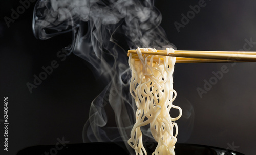 Canvas Print Chopsticks noodles with steam and smoke on black background