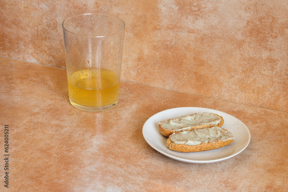 A small plate with two whole wheat toast with cream of Cabrales cheese with cider near a glass of cider with a shot of cider on an abstract studio background. A delicious and typical Spanish snack. A small plate with two whole wheat toast with cream of Cabrales cheese with cider near a glass of cider with a shot of cider on an abstract studio background. A delicious and typical Spanish snack.